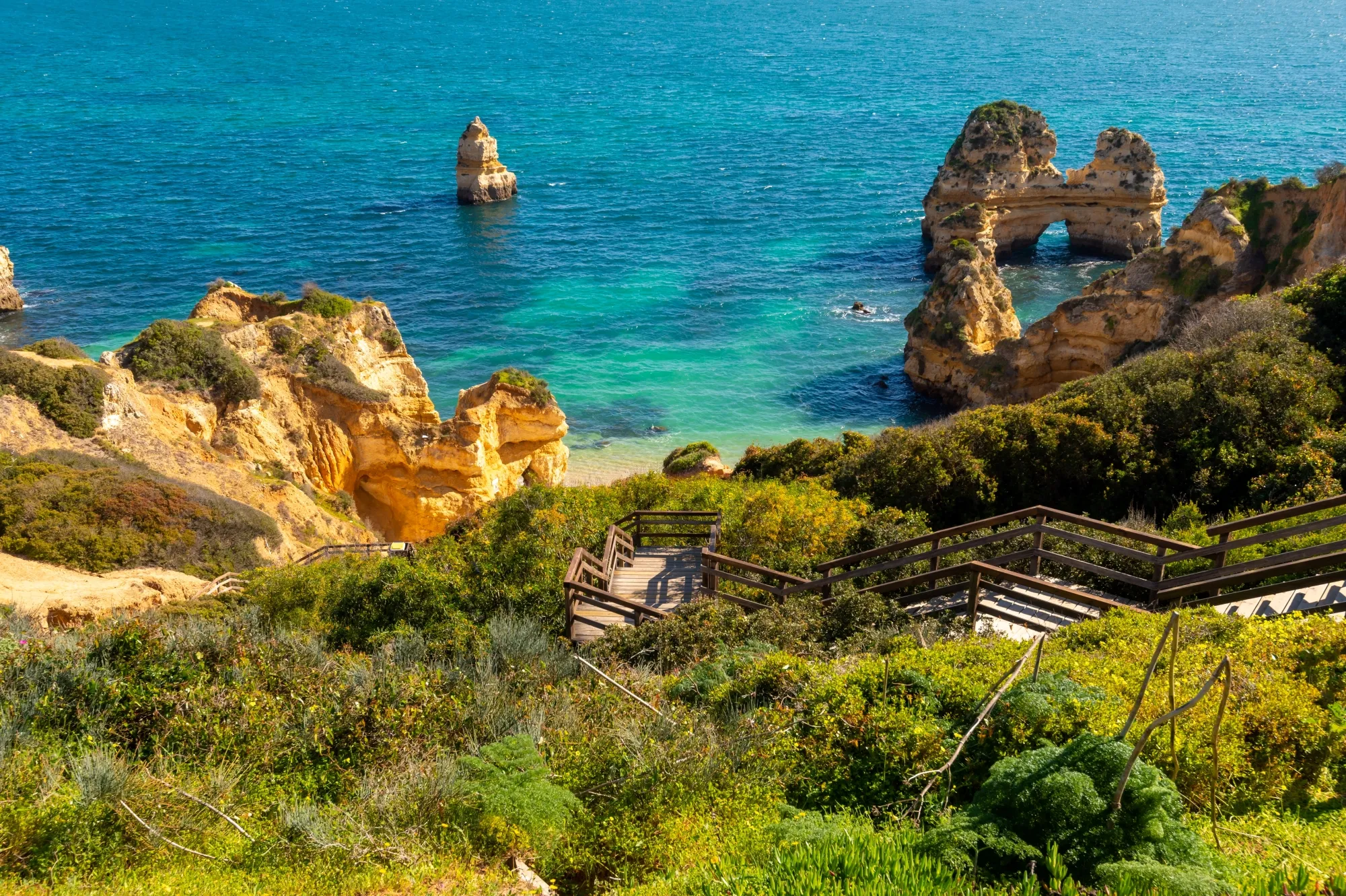 Golden limestone rock formations and turquoise waters at Algarve Portugal beach