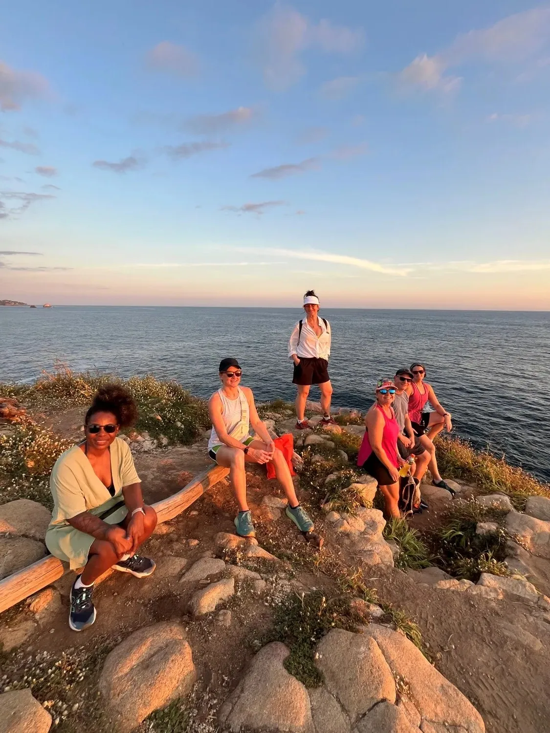 Friends relaxing on rocky tropical beach during small group wellness adventure vacation