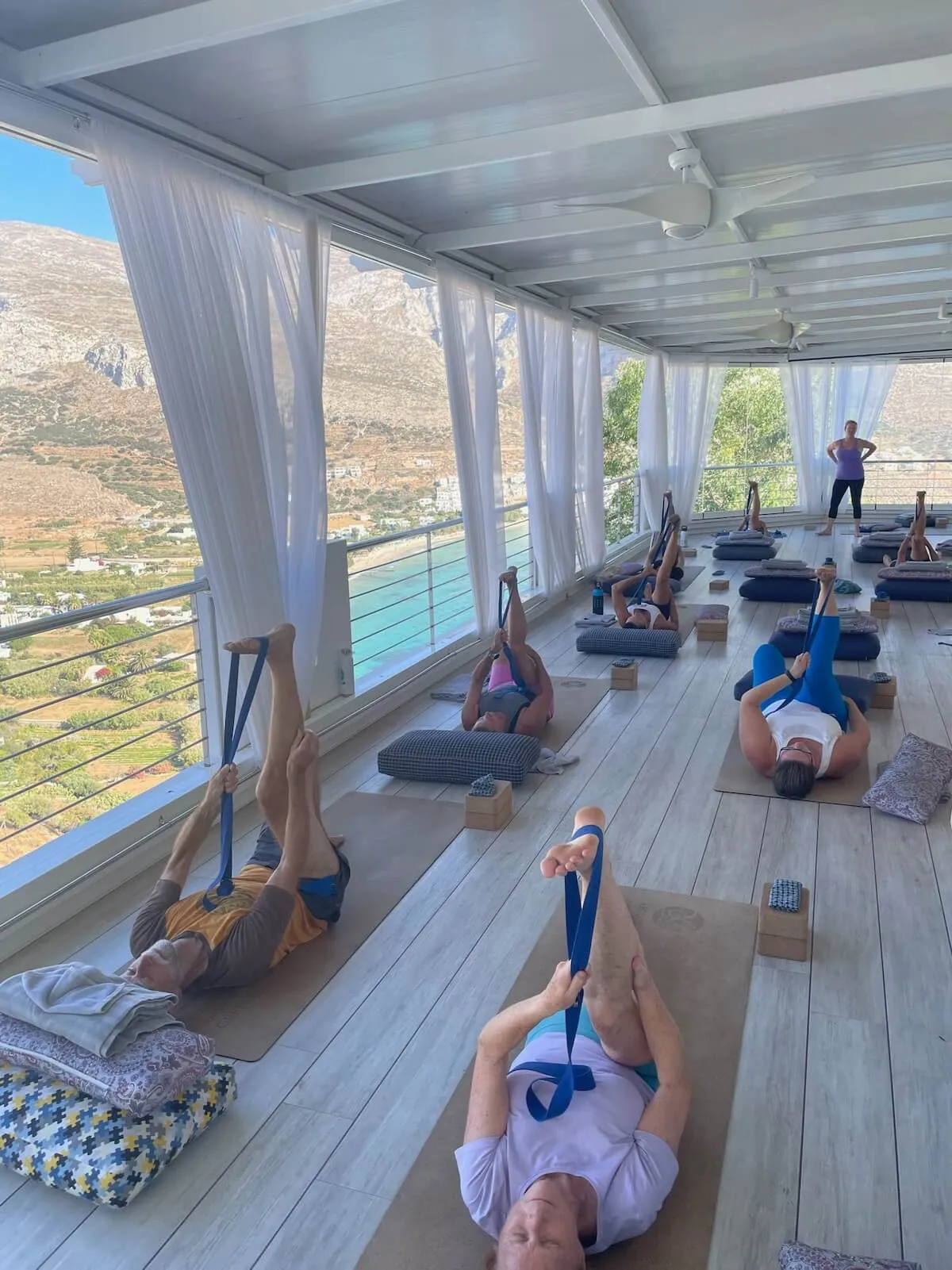 Traditional white-washed Greek courtyard with pink bougainvillea flowers and tables